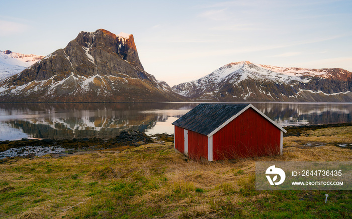 Traditional red wooden houses and mountains. Sunset sky with clouds. Travel in Scandinavia, Europe.