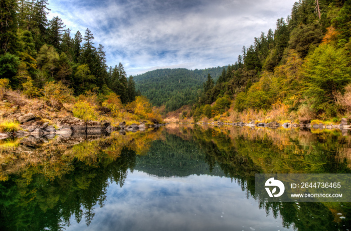 Orange and yellow fall colors reflect in the Rogue River on a calm section in the afternoon