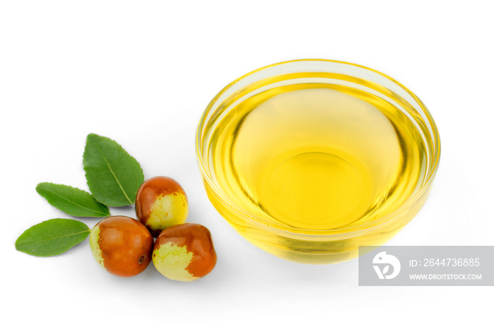 Bowl with jojoba oil, ripe fruits and green leaves on white background