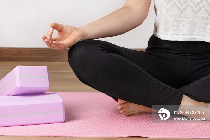 Yoga woman sitting in lotus asana and breathing. Yoga workout with yoga blocks.