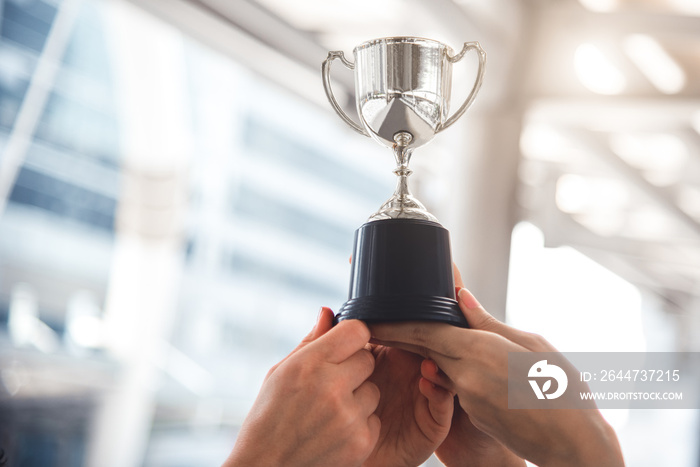 Champion silver trophy for runner up winner with sport player hands in sport stadium background. Success and achievement concept. Cup award theme. American football award and match game play prize