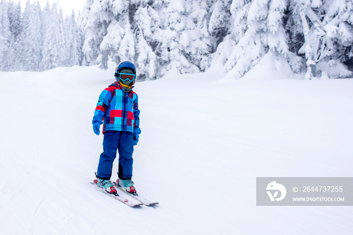 Child skiing in mountain resort during winter season