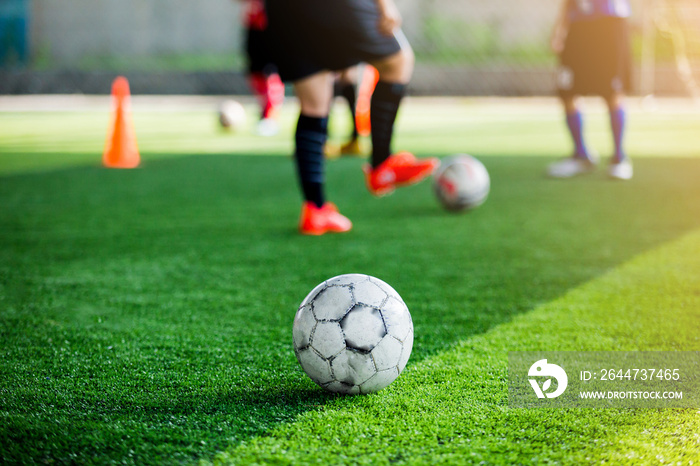 Football on green artificial turf with blurry of soccer players are training