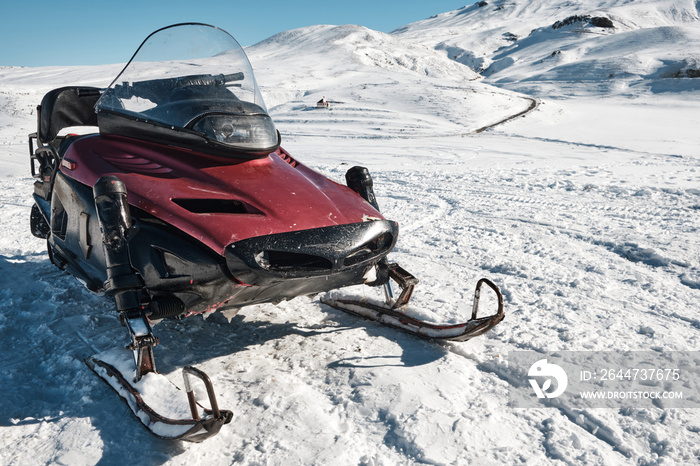 Snowmobile against snow covered slope at background. Snow vehicle