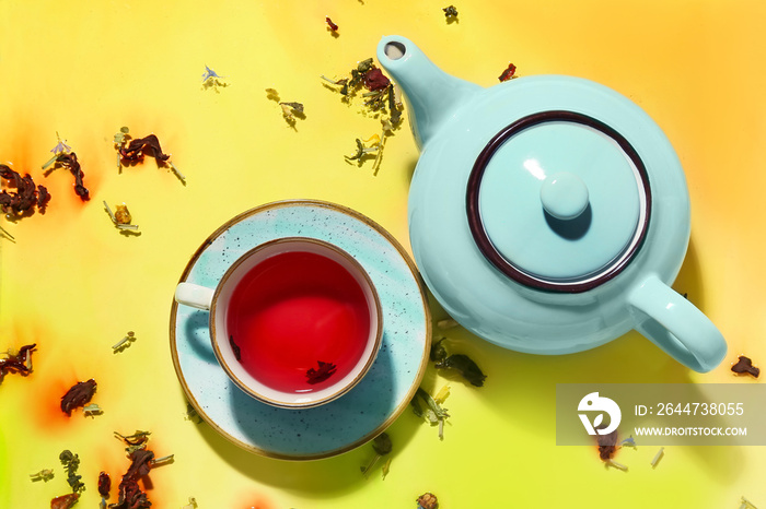 Tea pot and cup of hot red tea on color background