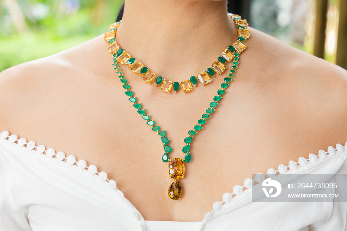 A necklace made of emeralds and amber on the neck of a beautiful woman.