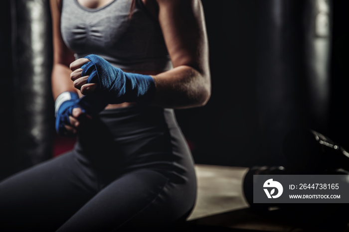 Woman wraps her fists in pink bandages for boxing gloves