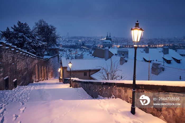 Cityscape of Prague in winter. Snow covered staircase ​against Lesser Town early morning.