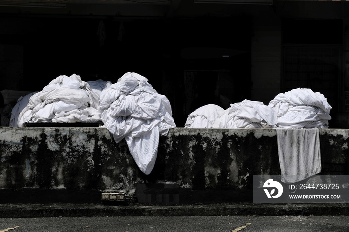 Dirty bedsheets and linens from nearby budget hotels and inns are being gathered and sorted out at the back of a commercial dry cleaning shop to be washed and cleaned.