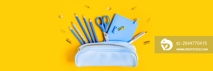 Web banner with School writing materials: pencils, scissors, notepad, pen case on yellow background.