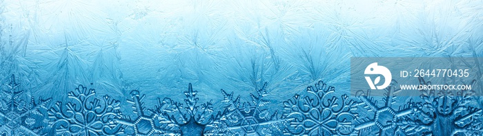 Wintry background with winter frost covered window with a pattern of ice crystals and clear snowflakes.