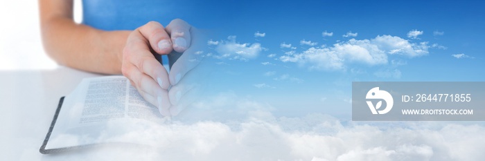 Composite image of clouds in the blue sky and hands praying over holy bible