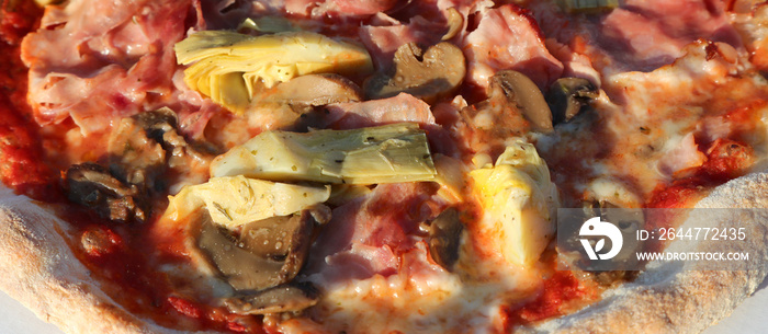 pizza called in Italy  capricciosa with mushrooms ham artichokes mozzarella tomato sauce cooked in a wood oven