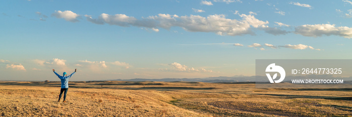 prairie in northern Colorado at early spring sunset with a lonely male figure - Soapstone Prairie Natural Area near Fort Collins with Rocky Mountains in background, panoramic web banner