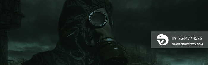 A man in a gas mask and a chemical protection suit. Man against the dark backdrop of a post-apocalyptic landscape. Nuclear war.