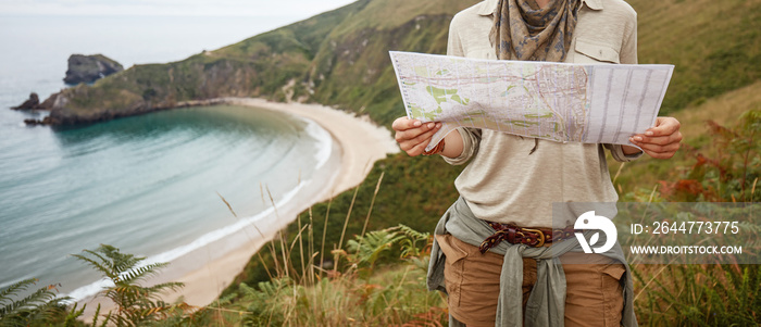 woman hiker looking at map in front of ocean view landscape