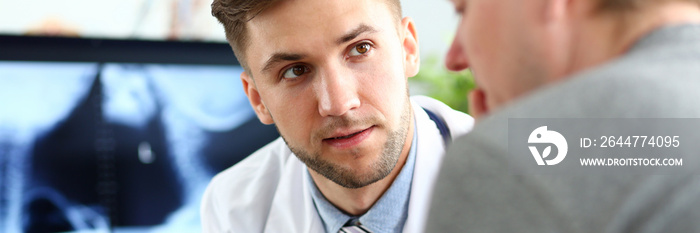 Handsome male doctor consulting patient showing something at tablet pc display