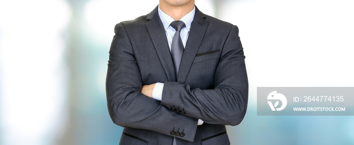 Anonymous businessman in dark gray suit crossing his arms