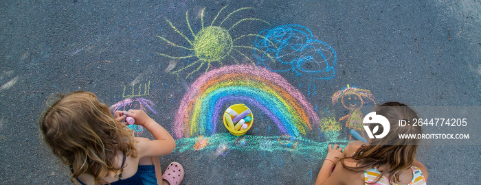 Children paint a rainbow on the asphalt. Selective focus.