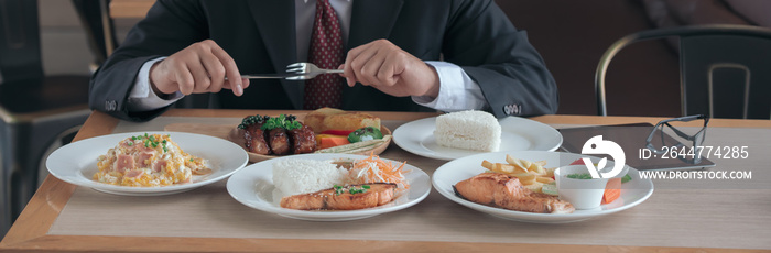 Man eating lots of food on the table with fired fish, pork steak, steam cooking rice, health care concept.