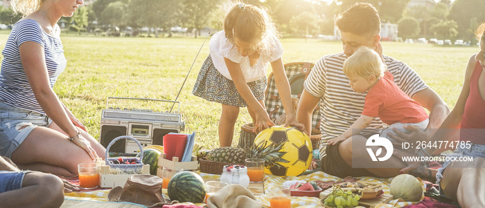 Happy families doing picnic in city park - Young parents having fun with their children in summer time eating, drinking and laughing together - Love and chlidood concept - Main focus on center people