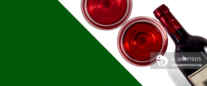 Bottle and two glasses of red wine. View from above. Green background - place for text.