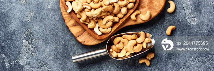 Roasted cashew nuts and scoop on gray background. Top view.