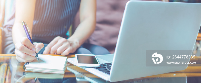 Business woman hand is writing on a notepad with a pen.