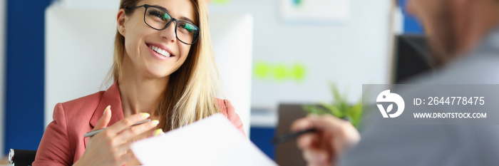 Smiling businesswoman with glasses communicating with colleague in office