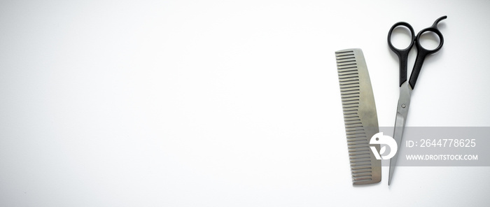 Metal comb with hairdressing scissors on a white background. An ad for a hairdressing salon. Barber’s tool on a white insulator