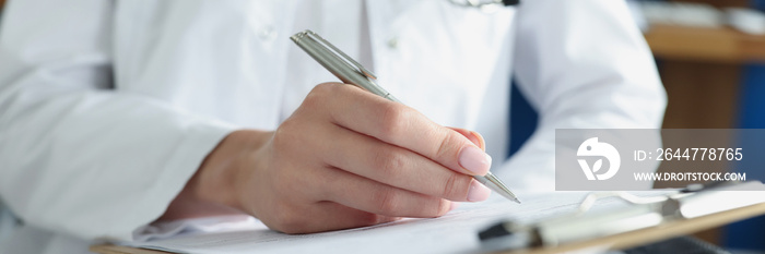 Doctor writing in medical documents on clipboard in clinic closeup