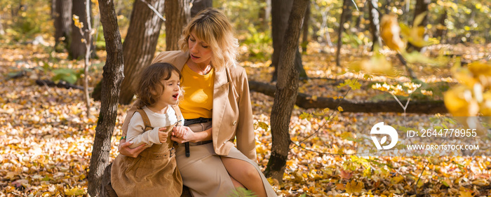 Banner mother comforting her crying little girl in autumn nature copy space. Emotions and family concept.