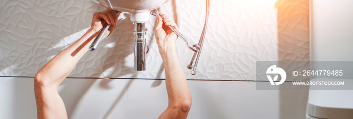 pure white bathroom with man plumbing hands that repairs the pipe of the soap box