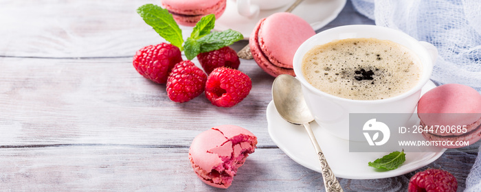 Cup of coffee with french raspberry macarons cookies on old white background. Holidays food concept,