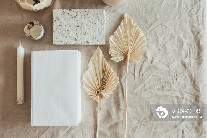 Lifestyle, still life composition with home decoration: book, fan leaves, granite brick, bust, candl