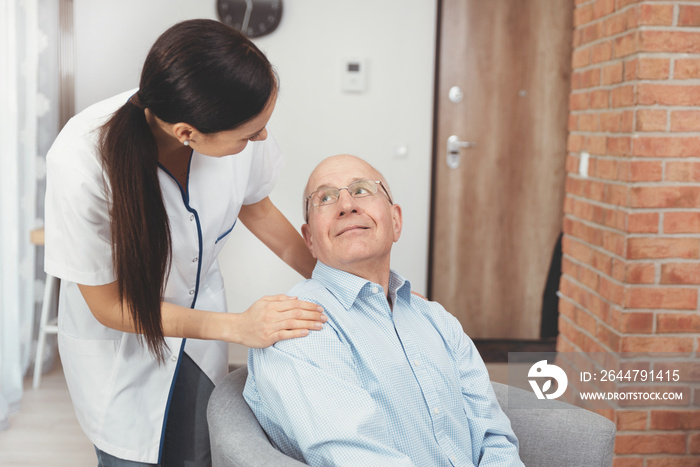 Smiling nurse and old senior man patient at home