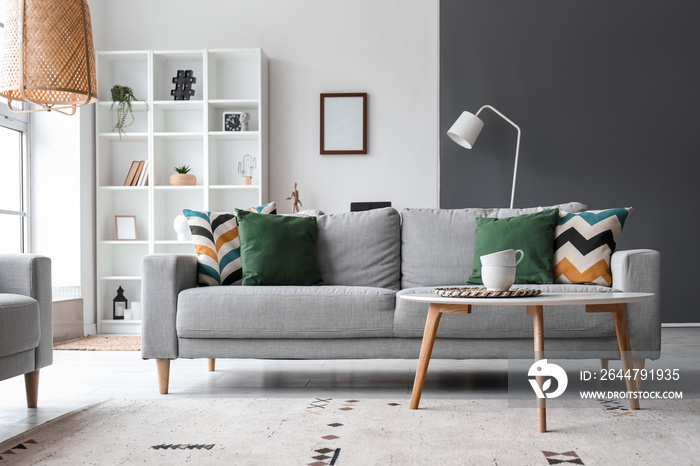 Interior of modern living room with grey sofa, table and shelving unit