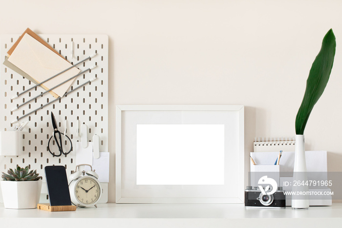 White home office desk with photo frame, supplies, flower. Minimal blank frame mockup design.