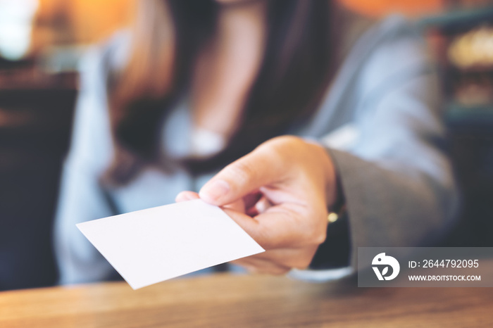 A beautiful Asian business woman holding and giving empty business card in modern loft cafe