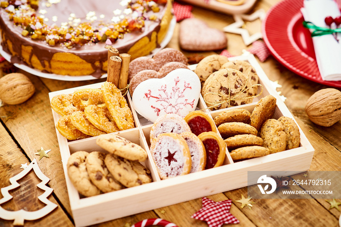 old wooden table with delicious Christmas cookies in a box and various decorations