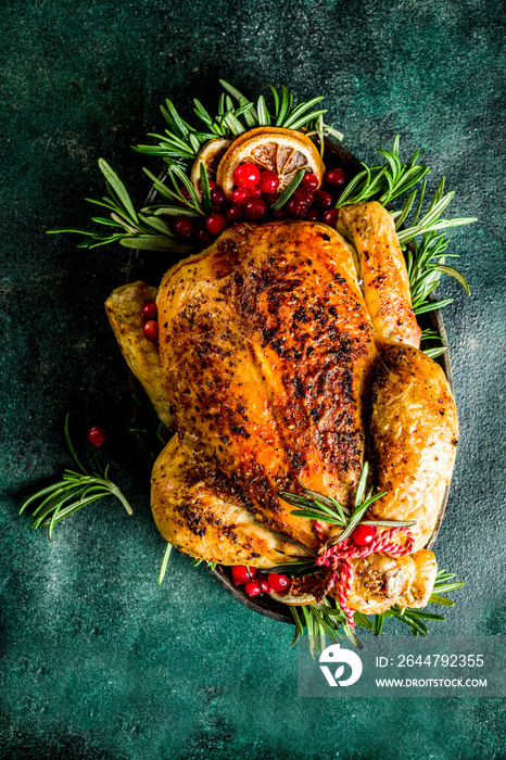 Traditional Christmas and Thanksgiving roasted whole chicken with fruit and rosemary. Dark green con