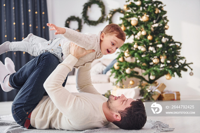 Father having fun with his son indoors in the christmas decorated domestic room