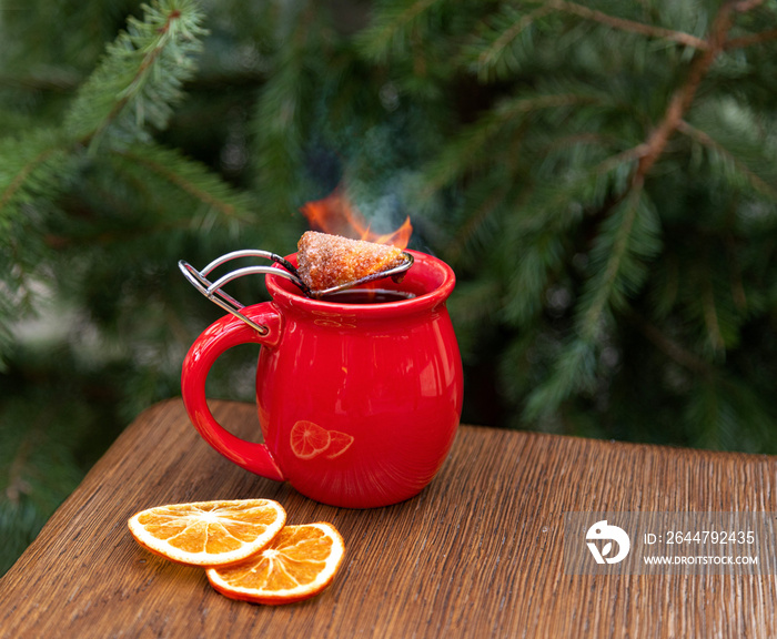 hot mulled wine with a burning piece of sugar on the background of a Christmas tree