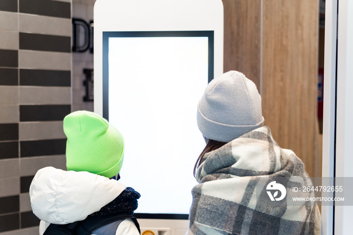 Self service restaurant, kiosk, terminal. Two girls near an empty screen order food