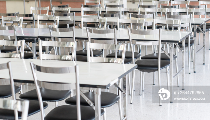 Stainless steel tables and chairs in high school student canteen, public cafeteria room interior bac