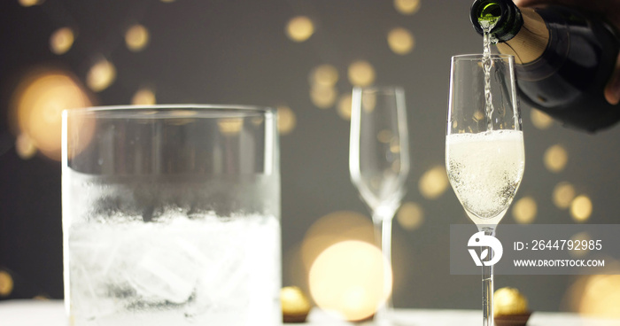 Bottle of sparkling wine with three flute glasses with bubbles floating up on gray backgrounds with 