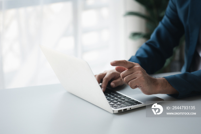 Person typing on laptop keyboard and pointing at screen, businessman working on laptop, he is typing