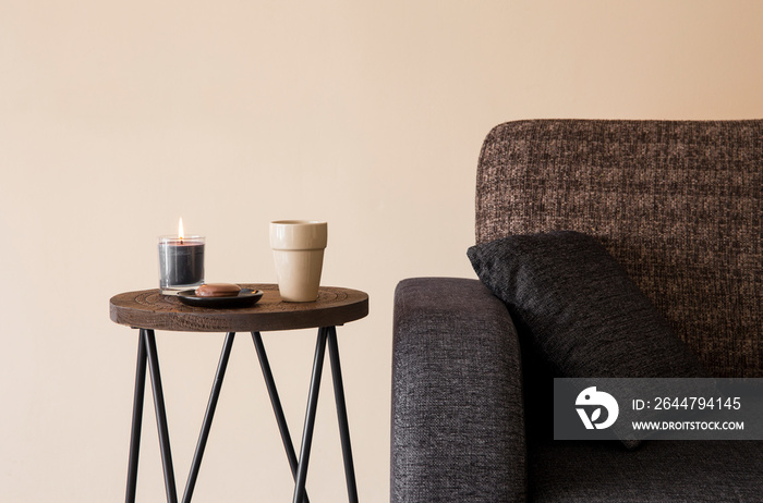 Detail view of modern round wood metal coffee table with cappuccino mug, glass candle burning by the