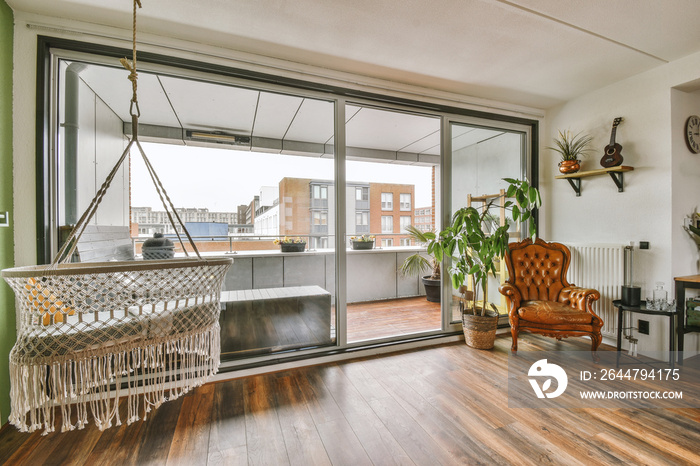 Modern loft-style room with parquet flooring with large panoramic windows and a balcony behind a gla