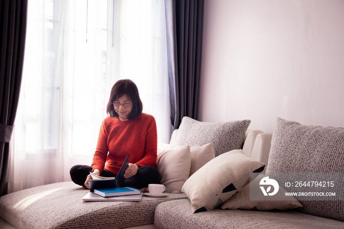 Beautiful girl at home sitting on the couch, reading a book.